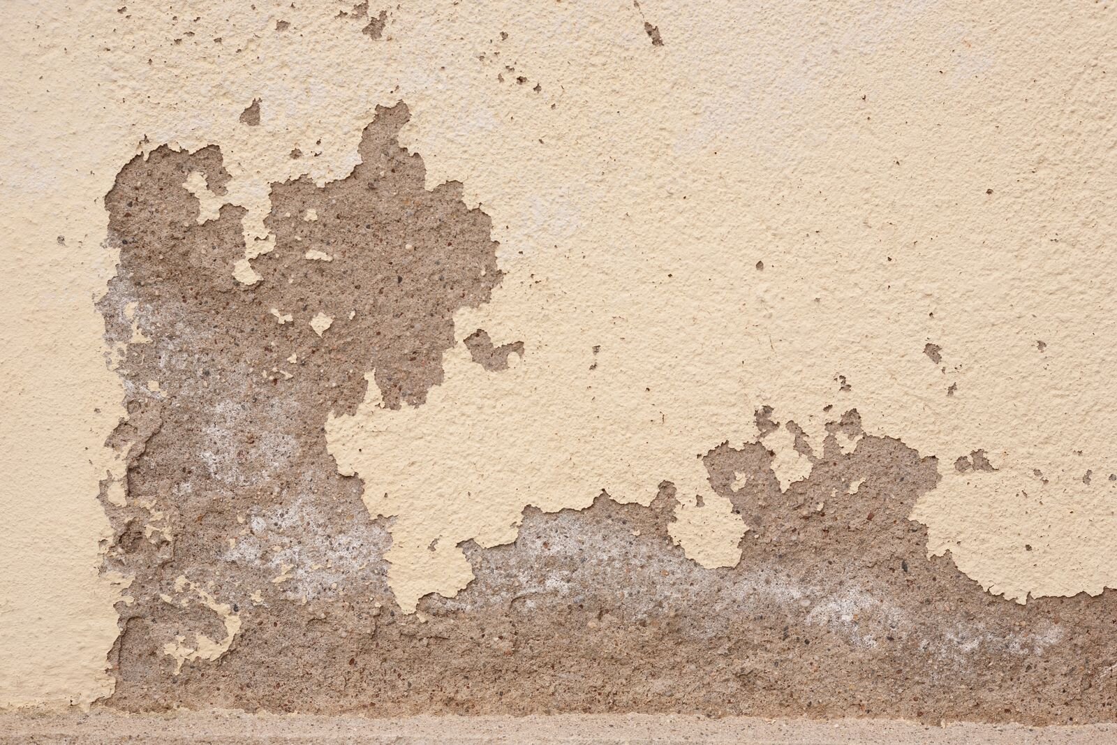 Enduit dégradé dans la partie basse d'un mur